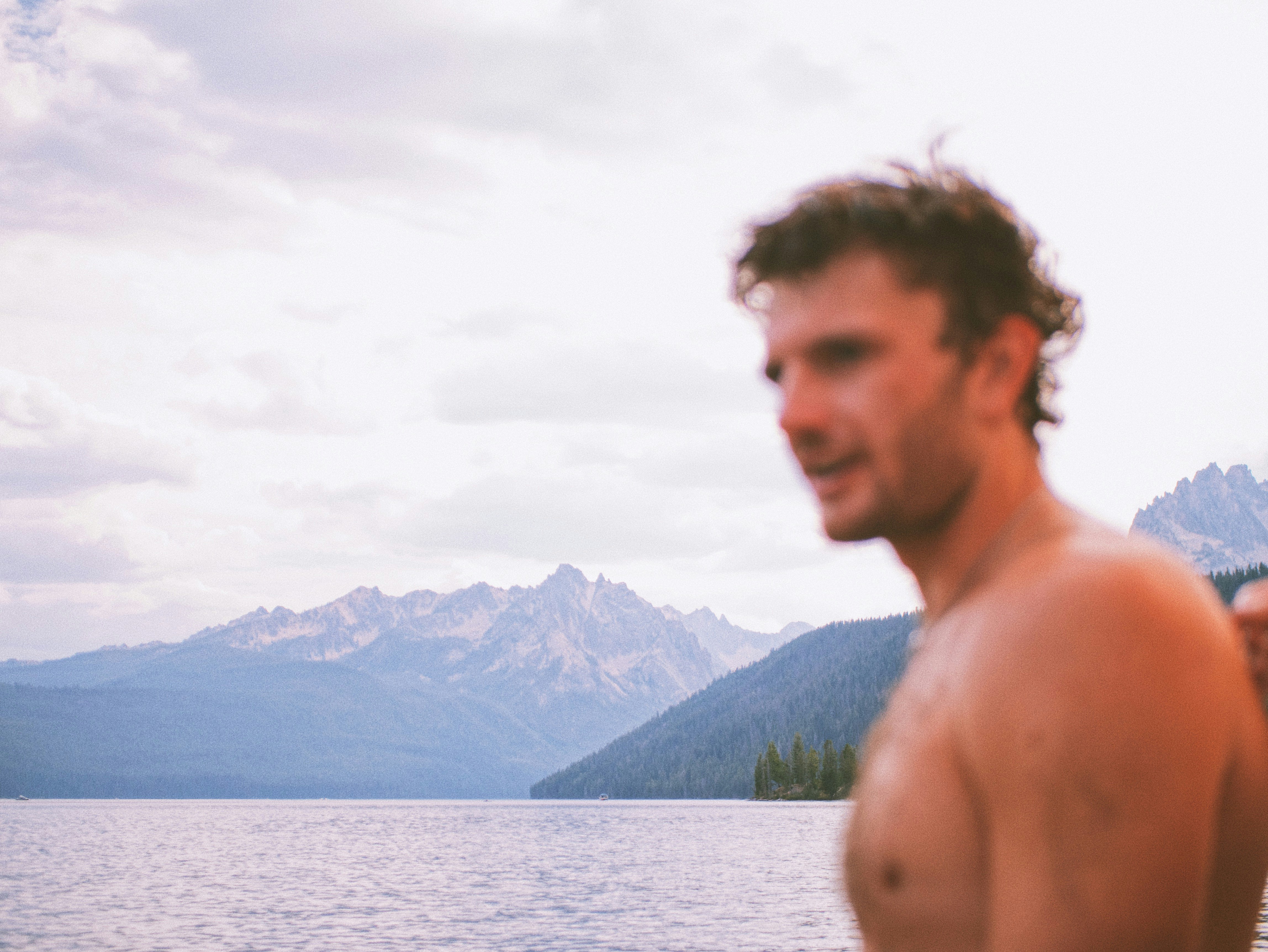 topless man standing near body of water during daytime